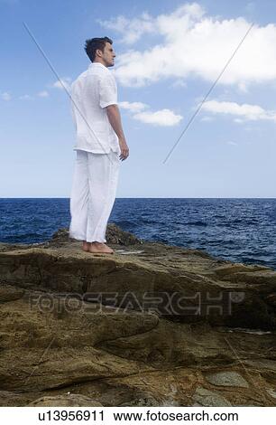 Stock Image - A man standing by the sea. Fotosearch