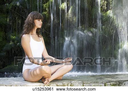 A woman meditating by a waterfall View Large Photo Image Stock Image - A woman meditating by a waterfall. Fotosearch