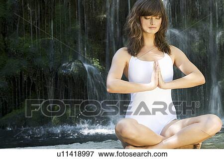 A woman meditating by a waterfall View Large Photo Image Stock Photo - A woman meditating by a waterfall. Fotosearch