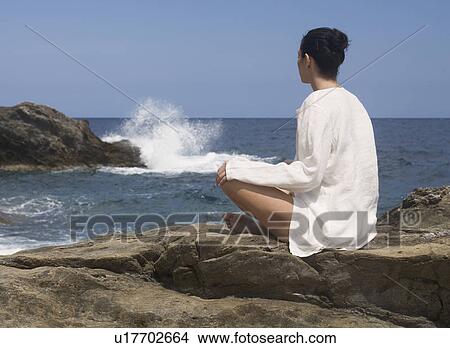 Picture - A woman meditating by the sea. Fotosearch
