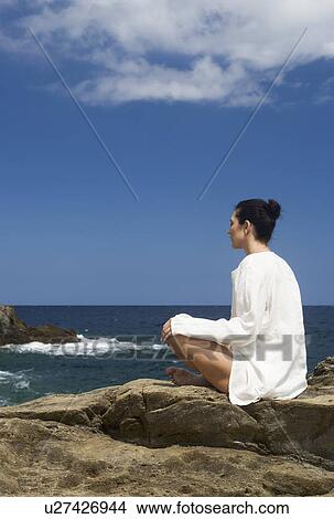 Picture - A woman meditating by the sea. Fotosearch