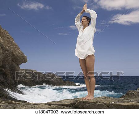 Stock Image - A woman meditating by the sea. Fotosearch