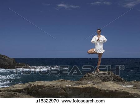 Stock Image - A woman meditating by the sea. Fotosearch