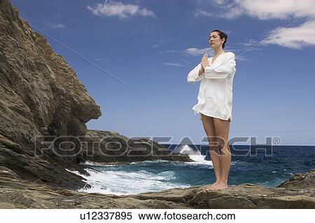 Stock Photography - A woman meditating by the sea. Fotosearch