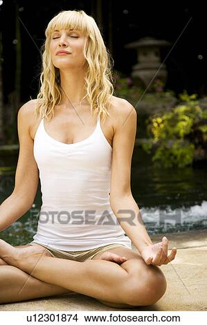 Beauty portrait of a woman in the lotus position doing yoga in a tropical setting. View Large Photo Image Picture - Beauty portrait of a woman in the lotus position doing yoga in a tropical setting.. Fotosearch