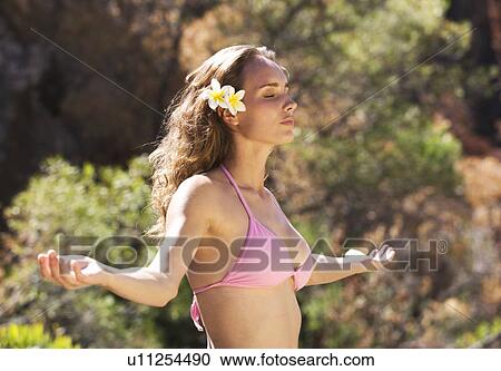 Stock Image - Young woman in a bikini meditating. Fotosearch