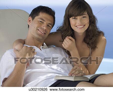 Stock Photograph - A couple relaxing by a pool. Fotosearch
