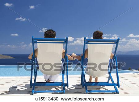 Stock Image - A couple relaxing in deck chairs. Fotosearch