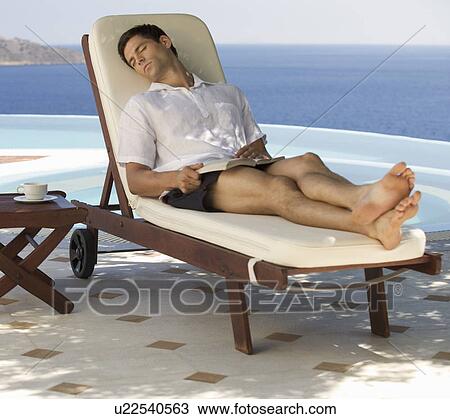 Stock Image - A man relaxing by a pool. Fotosearch