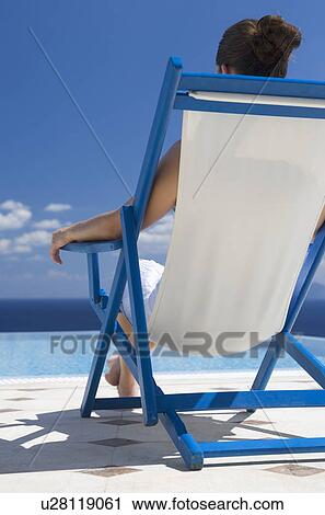 Stock Image - A woman relaxing in a deck chair. Fotosearch