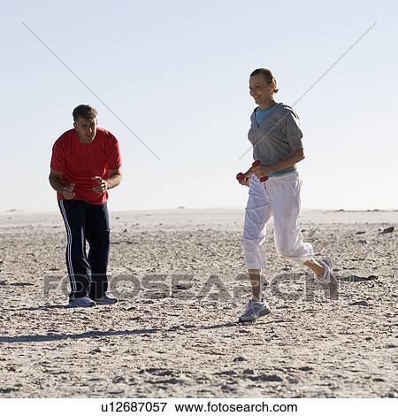 Stock Photo - A mature couple exercising on a beach. Fotosearch