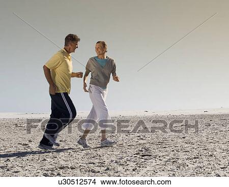 A mature couple jogging on a beach View Large Photo Image Picture - A mature couple jogging on a beach. Fotosearch
