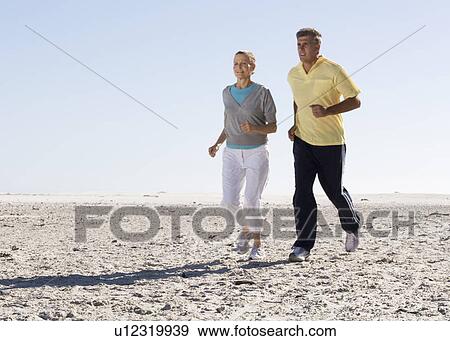 A mature couple jogging on a beach View Large Photo Image Stock Photo - A mature couple jogging on a beach. Fotosearch