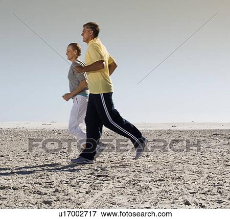 A mature couple jogging on a beach View Large Photo Image Stock Photo - A mature couple jogging on a beach. Fotosearch