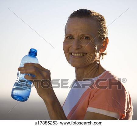 Stock Image - A mature woman drinking a bottle of water. Fotosearch
