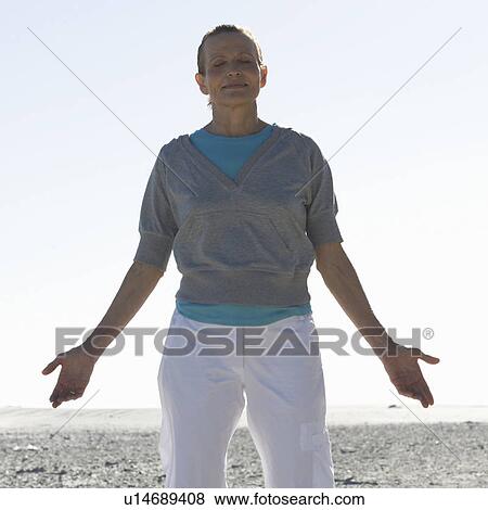 A mature woman meditating on a beach View Large Photo Image Stock Photo - A mature woman meditating on a beach. Fotosearch