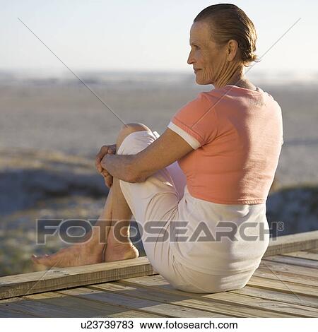 A mature woman sitting on a boardwalk View Large Photo Image Stock Image - A mature woman sitting on a boardwalk. Fotosearch
