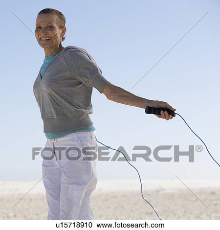 Stock Image - A mature woman skipping. Fotosearch