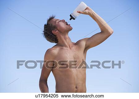 A young man drinking from a water bottle after exercising View Large Photo Image Stock Photography - A young man drinking from a water bottle after exercising. Fotosearch