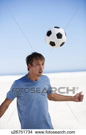 Picture - A young man playing with a football. Fotosearch