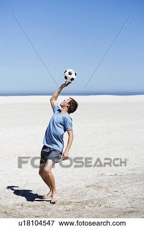 Stock Photo - A young man playing with a football. Fotosearch