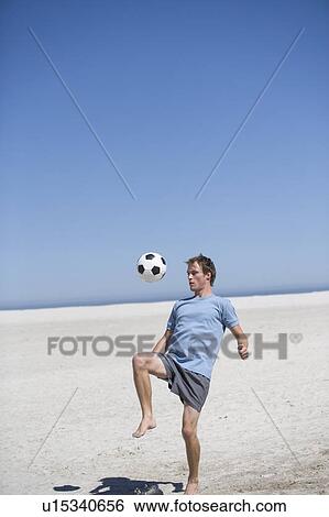 Stock Photograph - A young man playing with a football. Fotosearch