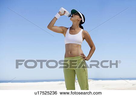 A young woman drinking from a water bottle after exercising View Large Photo Image Stock Photograph - A young woman drinking from a water bottle after exercising. Fotosearch