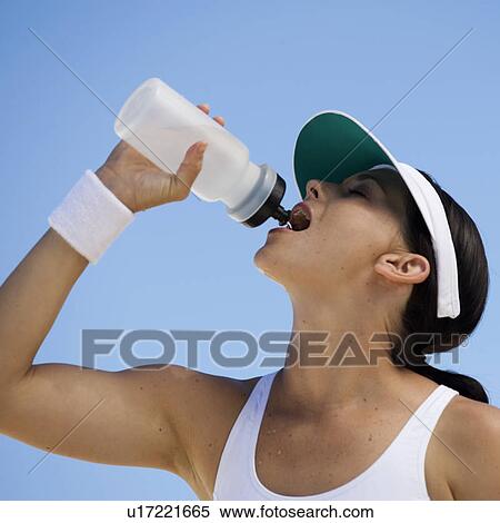 A young woman drinking from a water bottle after exercising View Large Photo Image Stock Photography - A young woman drinking from a water bottle after exercising. Fotosearch