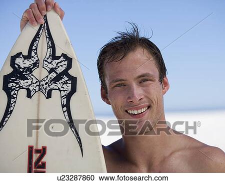Stock Image - Portrait of a young man with a surf board. Fotosearch