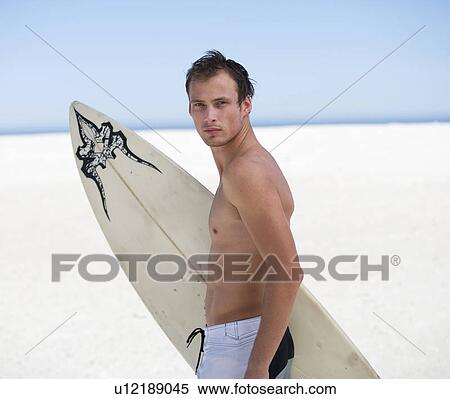 Stock Photography - Portrait of a young man with a surf board. Fotosearch
