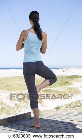 Young woman performing yoga on a beach View Large Photo Image Stock Image - Young woman performing yoga on a beach. Fotosearch