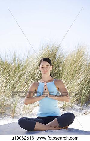 Young woman performing yoga on a beach View Large Photo Image Stock Photograph - Young woman performing yoga on a beach. Fotosearch