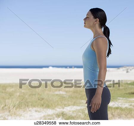 Stock Photo - Young woman standing on a beach. Fotosearch