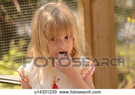 Blonde girl eating a cookie View Large Photo Image Stock Image - Blonde girl eating a cookie. Fotosearch