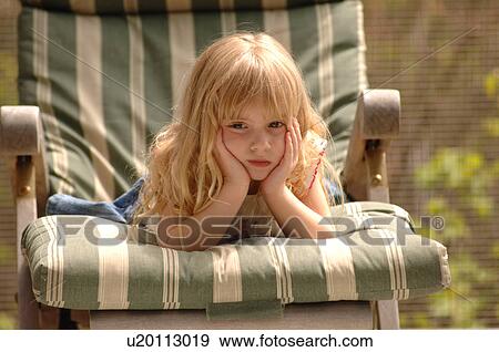 Blonde girl on chair with her hands to her face View Large Photo Image Stock Photo - Blonde girl on chair with her hands to her face. Fotosearch