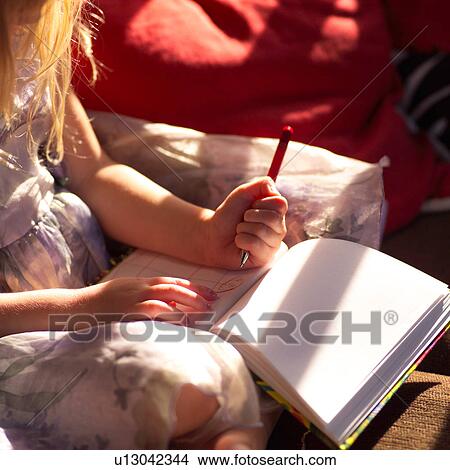 Picture - Child’s hand holding a pen and pad of paper. Fotosearch