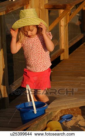 Young girl holding a straw hat looking down into a bucket View Large Photo Image Picture - Young girl holding a straw hat looking down into a bucket. Fotosearch