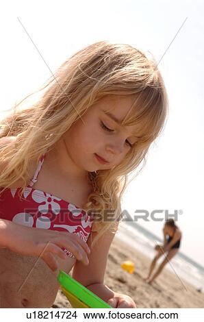 Young girl playing in sand on beach View Large Photo Image Picture - Young girl playing in sand on beach. Fotosearch