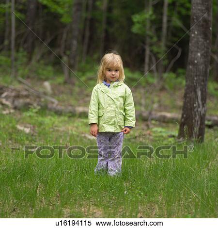 Stock Photography - Young girl standing in the woods looking at camera. Fotosearch