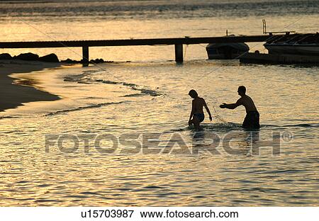A young couple playing in shallow sea water View Large Photo Image Stock Photo - A young couple playing in shallow sea water. Fotosearch