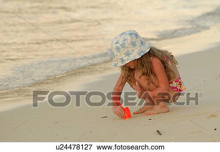 Stock Photo - Close-up of a young girl (6-8) playing on a beach. Fotosearch
