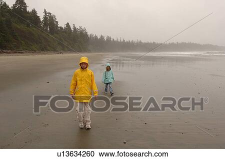 Stock Image - People walking on beach on a cloudy day. Fotosearch