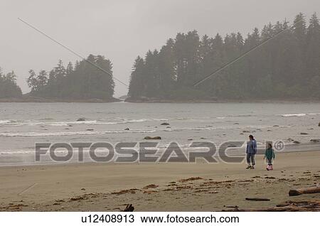 Stock Image - People walking on beach on a cloudy day, Florencia Bay, Vancouver Island, Canada. Fotosearch