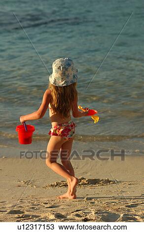 Stock Image - Rear of a young girl (6-8) on a beach. Fotosearch