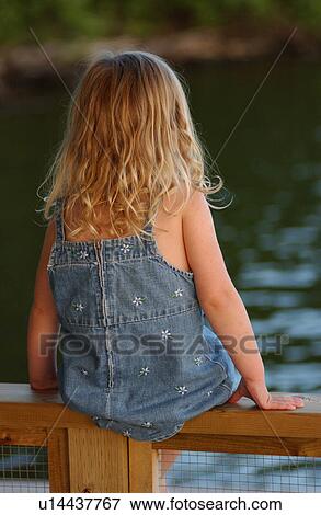Rear view of a young girl sitting on a wooden railing View Large Photo Image Stock Photo - Rear view of a young girl sitting on a wooden railing. Fotosearch