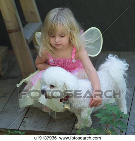 Stock Photograph - Young girl in a fairy costume holding a dog. Fotosearch