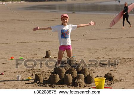 Young girl playing in sand on beach View Large Photo Image Stock Photography - Young girl playing in sand on beach. Fotosearch
