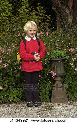 Stock Image - Young girl standing outdoors with a bag on her back. Fotosearch