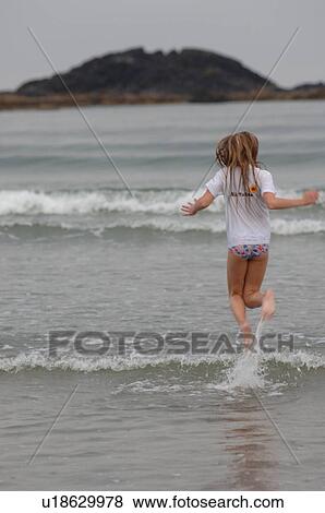 Stock Photo - Girl running through water, Wickaninnish Beach, Vancouver Island, Canada. Fotosearch