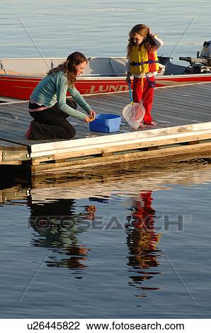 Stock Image - Two girls at edge of dock. Fotosearch
